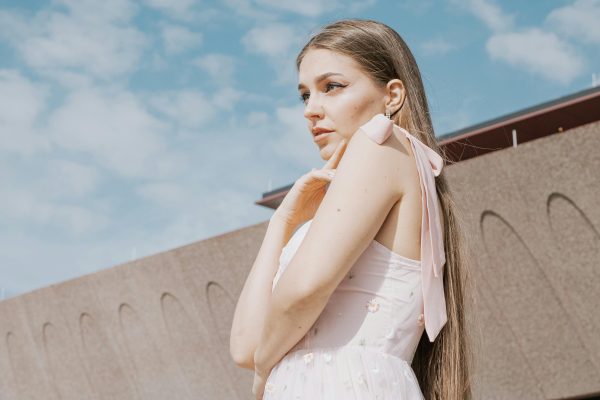 Outdoor portrait of a woman in a stylish pink dress, posing gracefully.